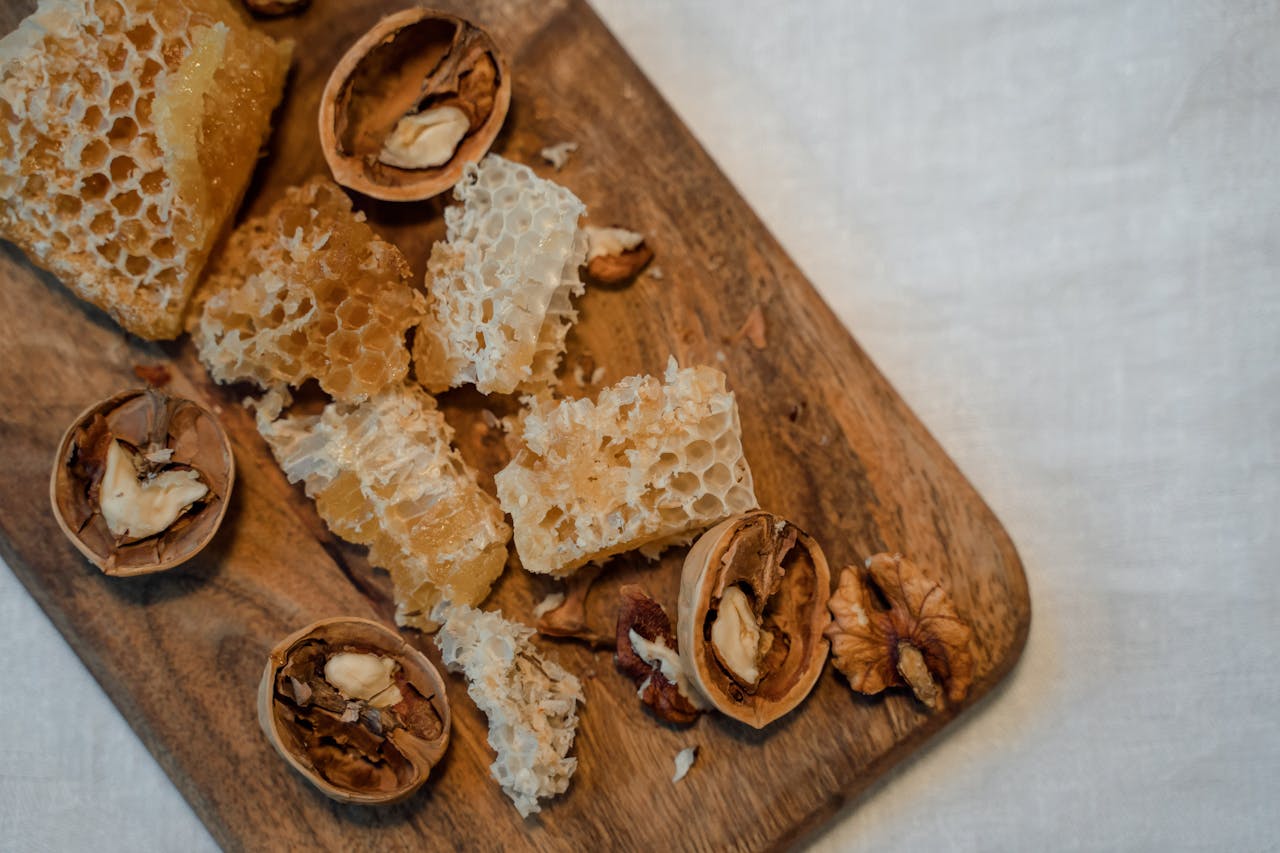 Close-up of honeycomb and walnuts on a rustic wooden board, top view.